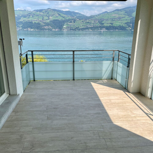 Modernen Balkon mit mega Aussicht auf den Thunersee. Feinste Feinsteinzeug Bodenplatten in Holzoptik verlegt für eine lange Lebensdauer.