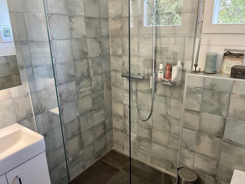 Dusche mit leicht türkis Platten in 20 x 20 und einem dunklen Boden aus Feinsteinzeug