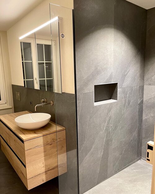 Neues Badezimmer mit Grossformatigen Fliesen in Schieferoptik aus feinstem Feinsteinzeug perfekt verlegt. Die moderne barrierefreie Dusche hat eine In-Box und moderne Armaturen in Chrom welche zu den dunklen Platten gut passen.