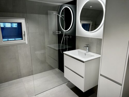Badezimmer in einem alten Bauernhaus komplett umgebaut zu einem Top modernen Badezimmer. Die Fliesen in Metaloptik in zwei Farben grau und anthrazit passen gut zusammen und mit LED Spiegel und weissen Möbeln ist wirkt der Raum grösser als vorher.