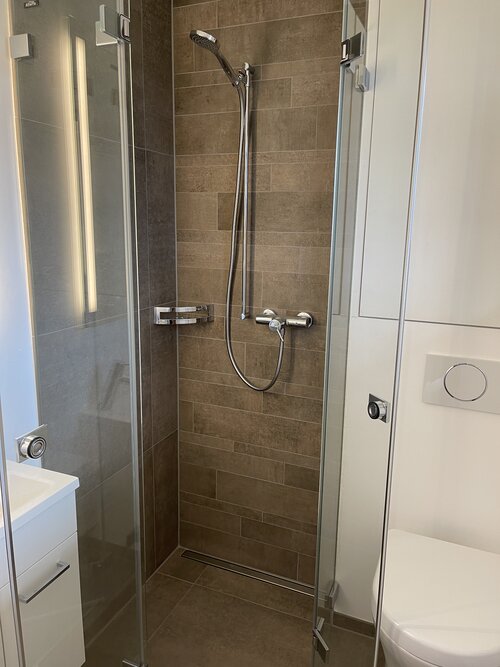 Dusche mit Feinsteinzeug Längsmosaik in braun.